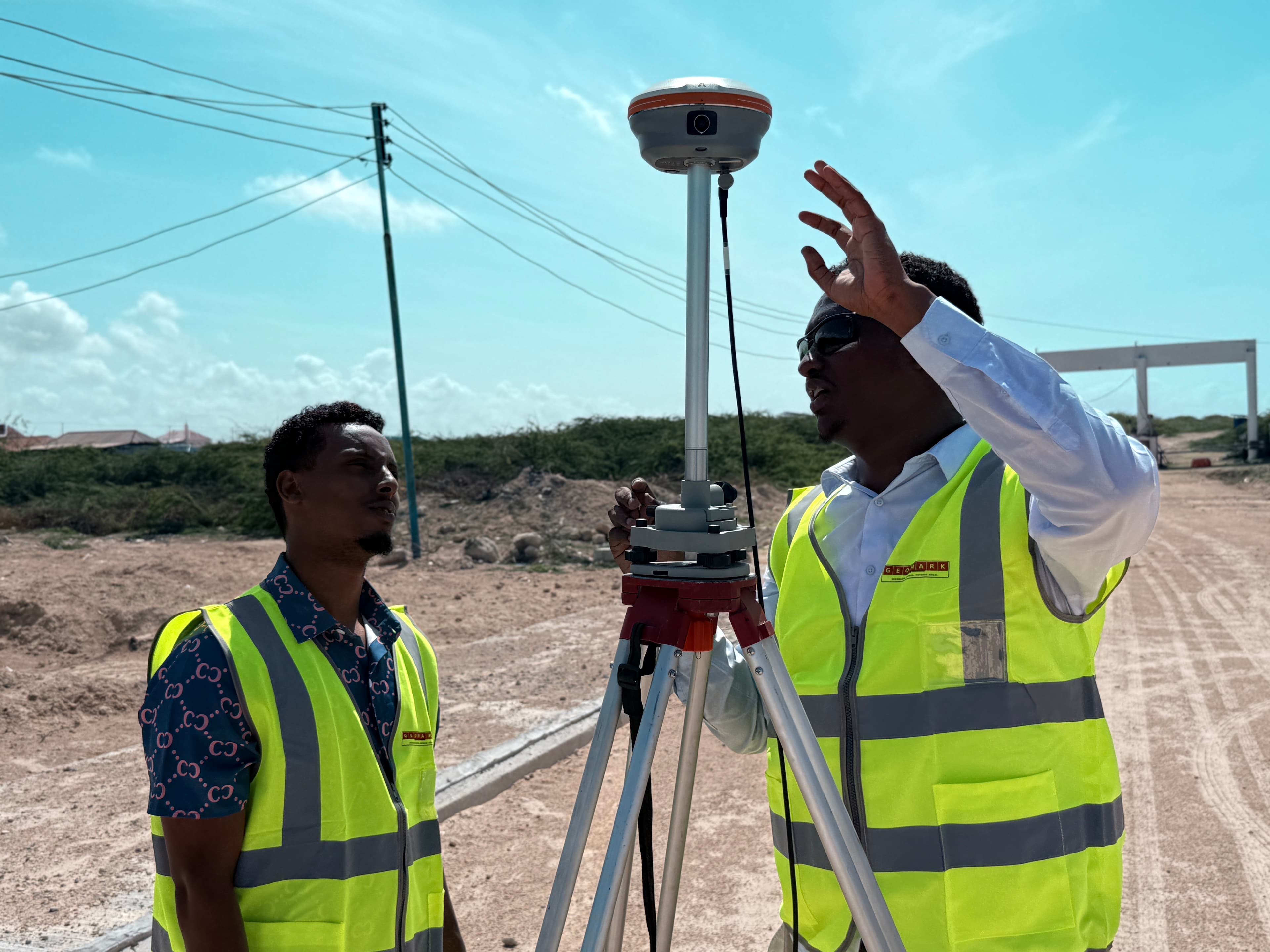 GEOMARK engineer with GNSS rover equipment briefing team on field survey