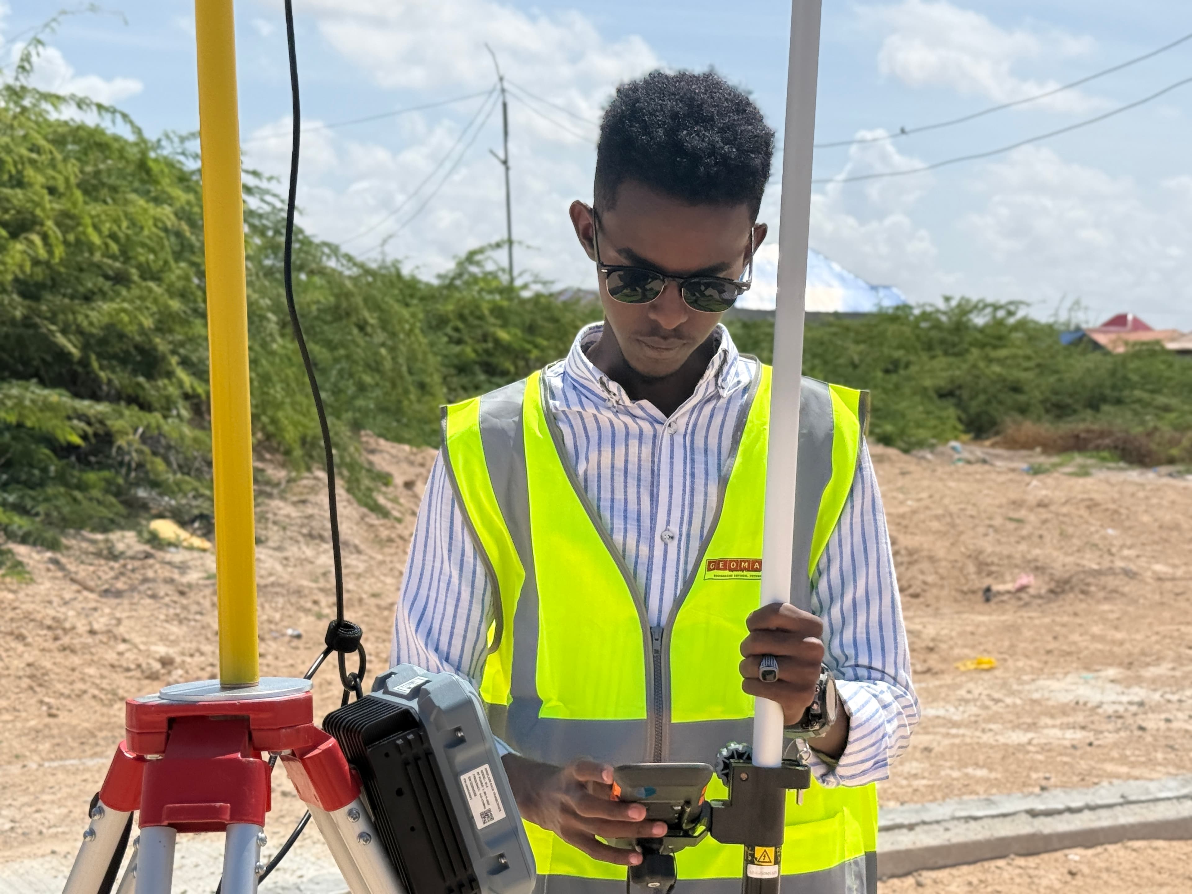 Engineer operating GNSS rover with data controller on corridor